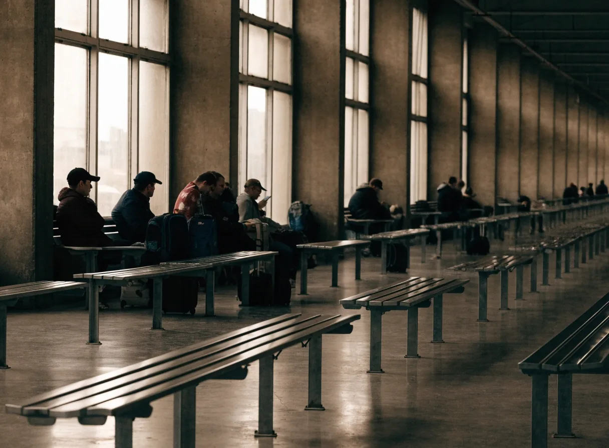 Wide eye-level view of a Czech station concourse floor in cold daylight, glass canopy casting long shadows across the polished slab