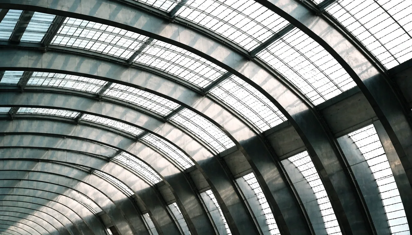Station hall arched roof seen from below with daylight entering in flat planes between the ribs