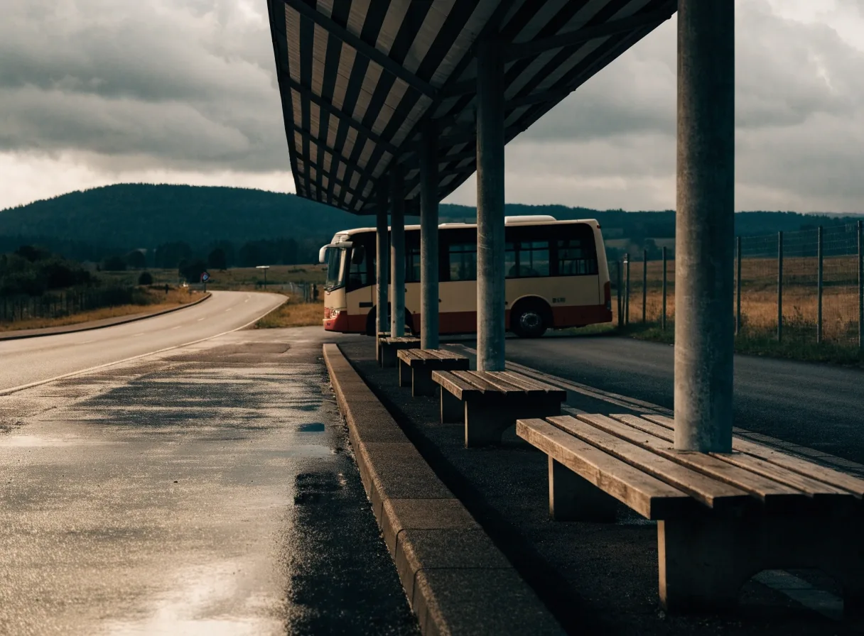 two travellers seen from behind at a station departure area, coats up, cool daylight through a glass wall