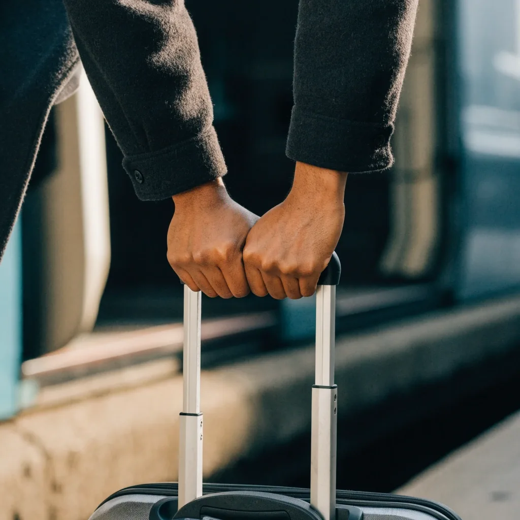 Hands folding a travel slip at waist level on a station platform in cool side daylight